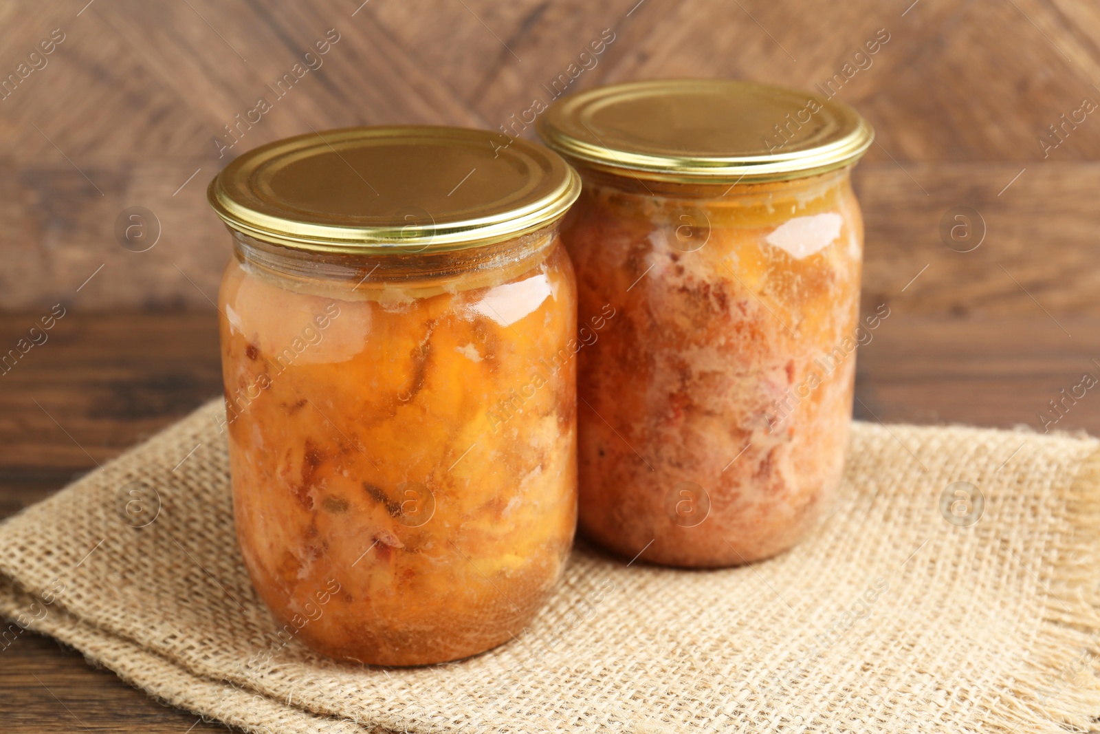 Photo of Canned meat in glass jars on wooden table, closeup