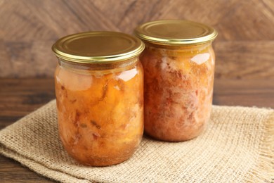 Canned meat in glass jars on wooden table, closeup