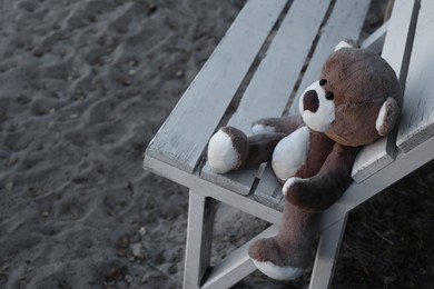 Photo of Lonely teddy bear on bench at beach