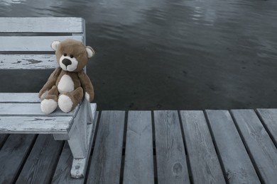 Photo of Lonely teddy bear on bench near river, space for text