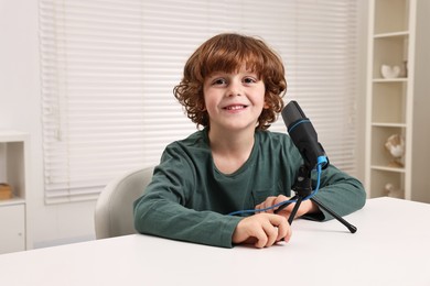 Photo of Little boy with microphone at white table indoors