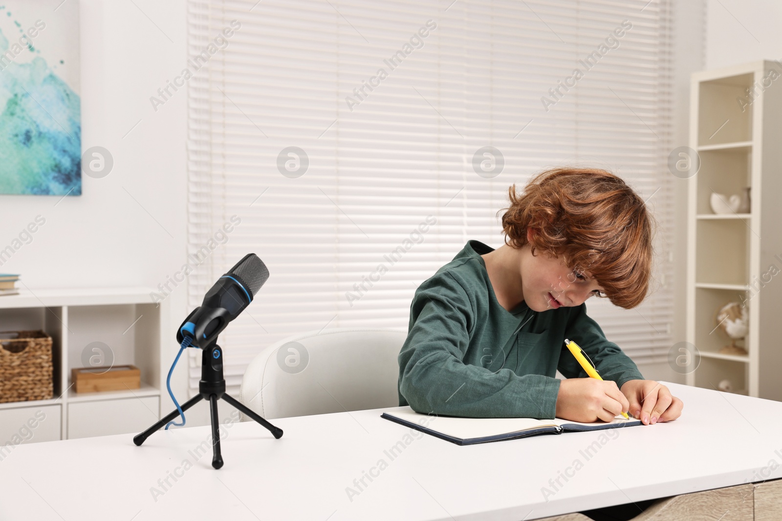 Photo of Little boy with microphone at white table indoors