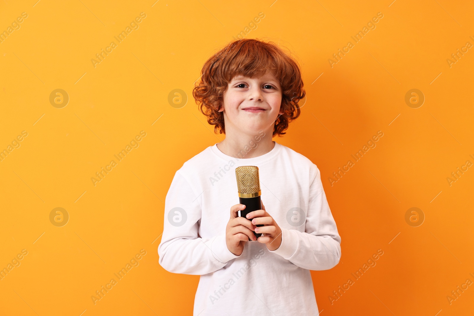 Photo of Little boy with microphone on orange background