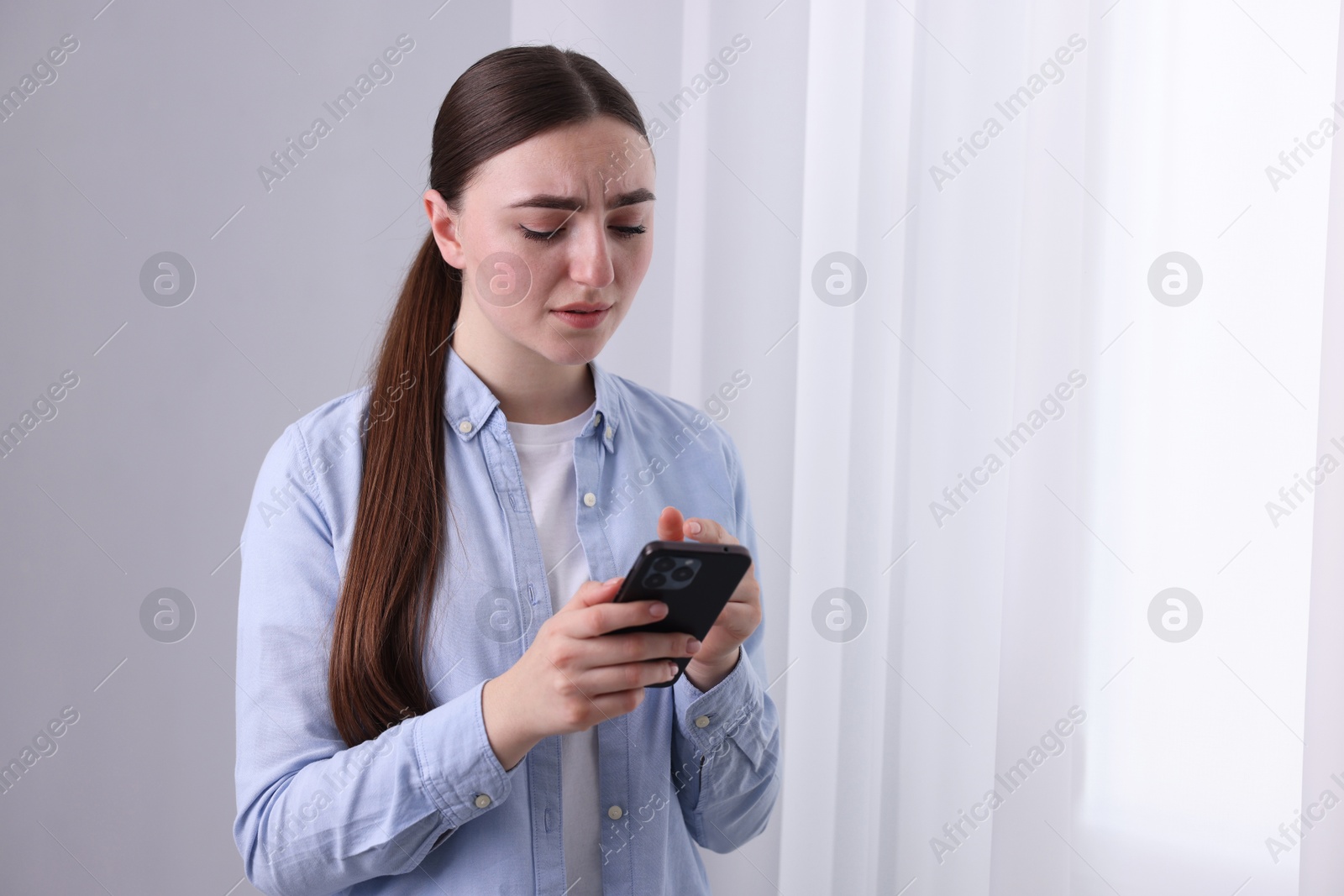 Photo of Stressed woman calling hotline for mental health help near window at home. Space for text