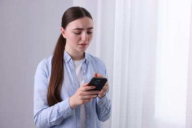 Photo of Stressed woman calling hotline for mental health help near window at home. Space for text