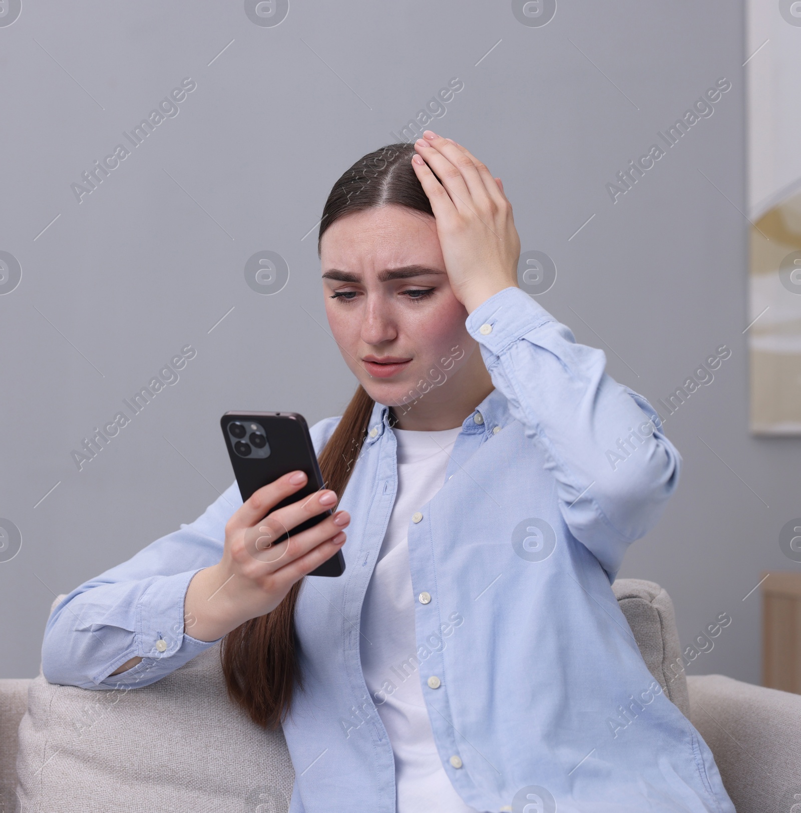 Photo of Depressed woman calling hotline for mental health help on sofa at home. Space for text