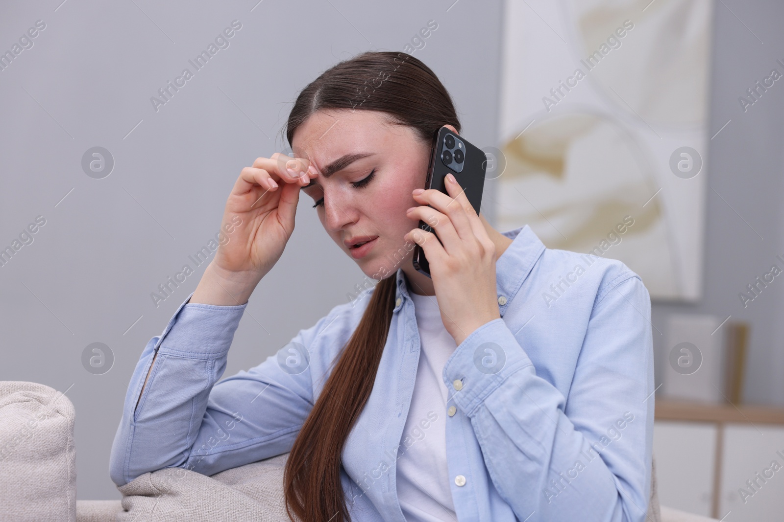 Photo of Stressed woman calling hotline for mental health help at home