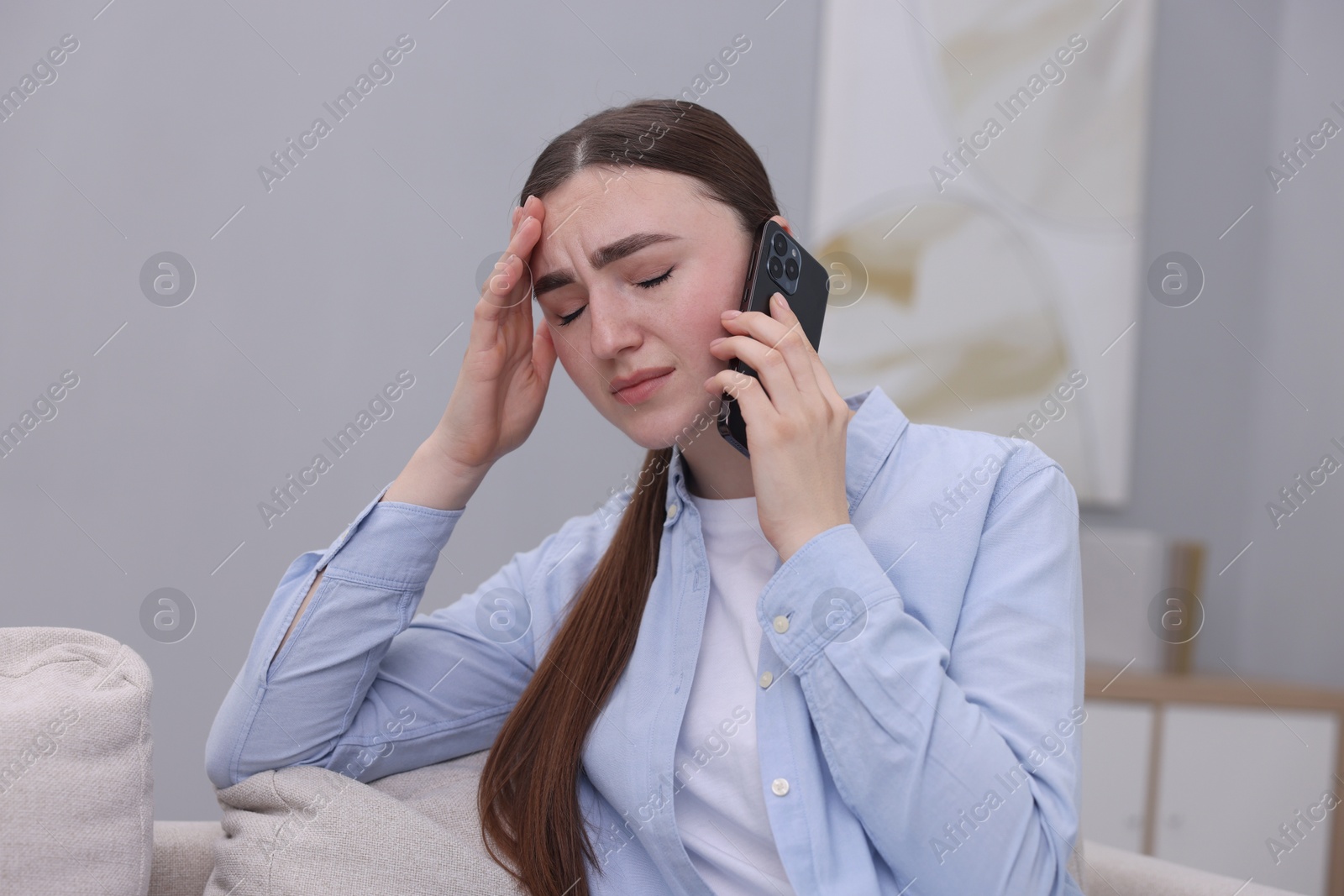 Photo of Stressed woman calling hotline for mental health help at home