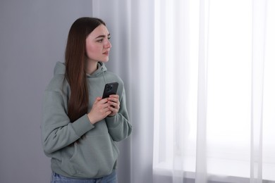 Photo of Desperate woman calling hotline for mental health help near window at home. Space for text