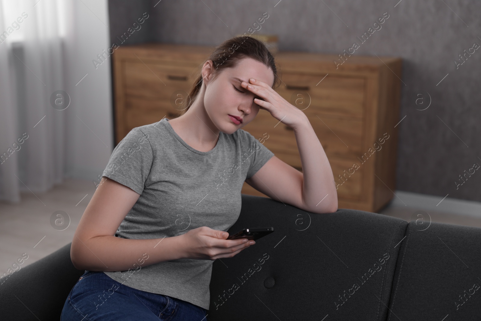 Photo of Depressed woman calling hotline for mental health help on sofa at home