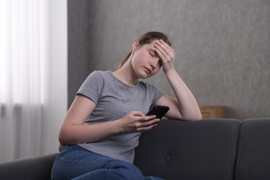 Photo of Depressed woman calling hotline for mental health help on sofa at home