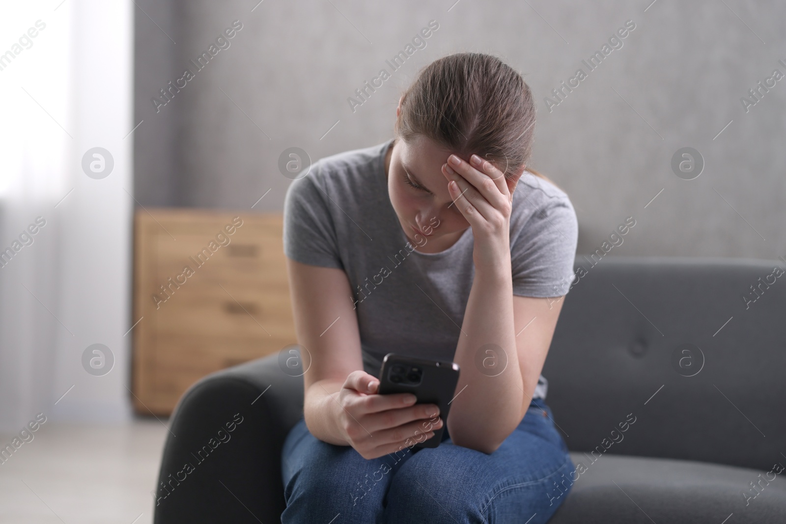 Photo of Depressed woman calling hotline for mental health help on sofa at home