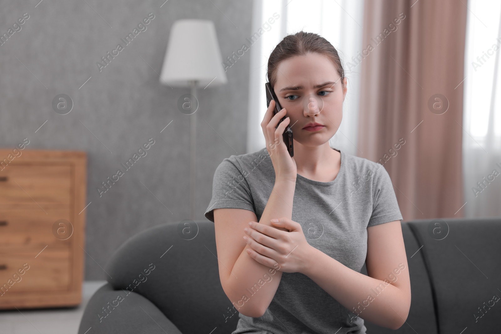 Photo of Depressed woman calling hotline for mental health help on sofa at home. Space for text