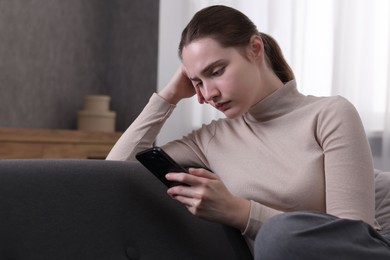 Photo of Depressed woman calling hotline for mental health help on sofa at home