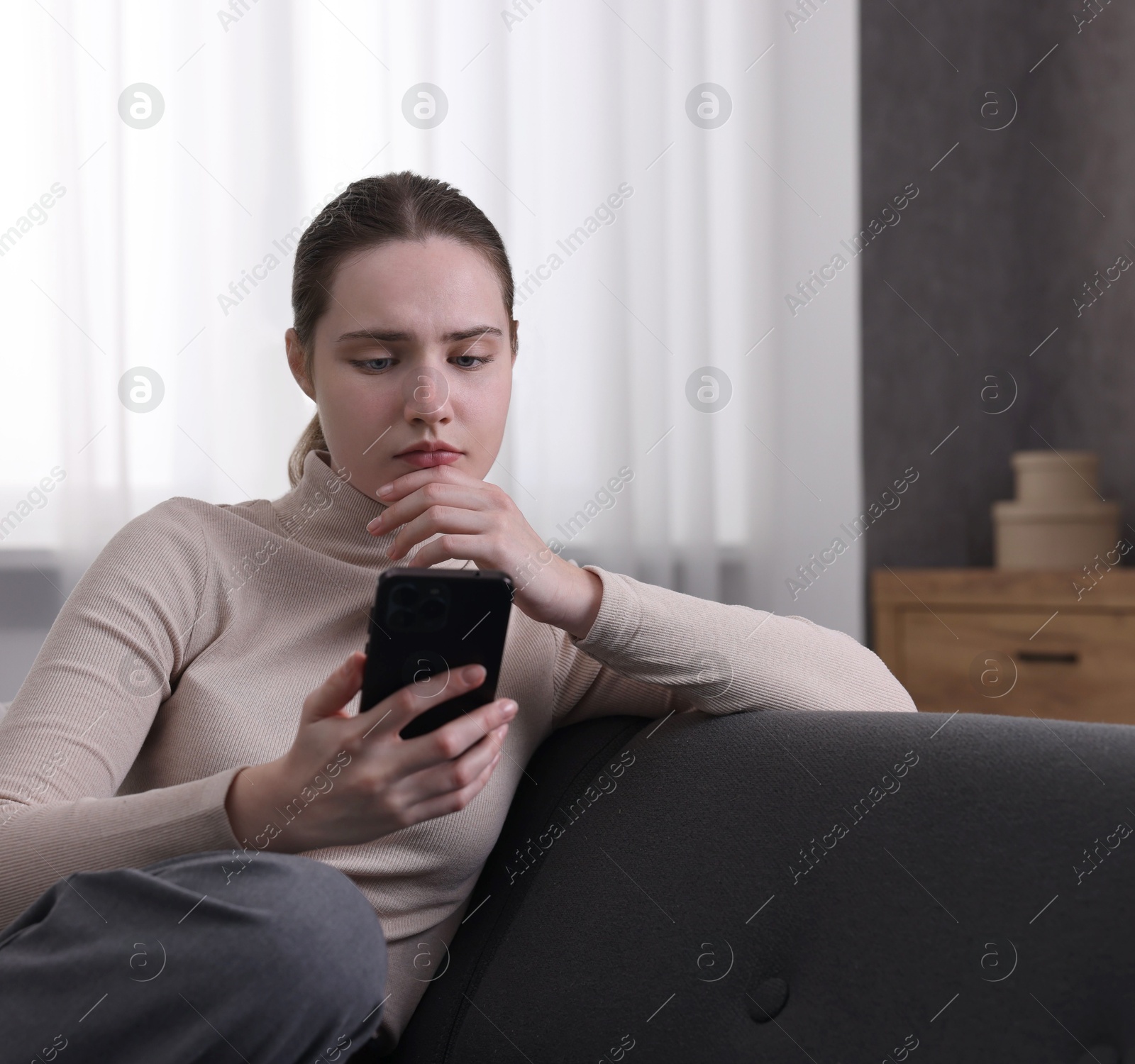 Photo of Depressed woman calling hotline for mental health help on sofa at home