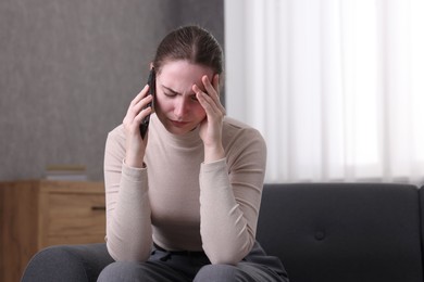 Photo of Depressed woman calling hotline for mental health help on sofa at home. Space for text