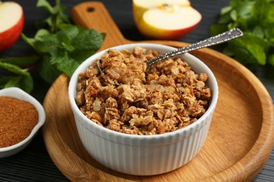 Photo of Delicious apple crisp in bowl and ingredients on table, closeup