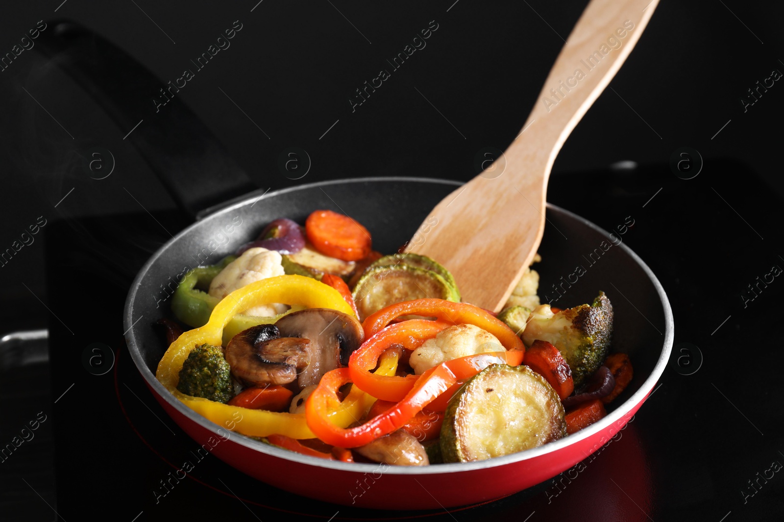 Photo of Frying pan with vegetables and mushrooms on stove, closeup