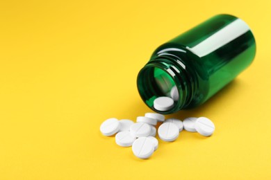 Photo of Medical bottle with antibiotic pills on yellow background. Space for text