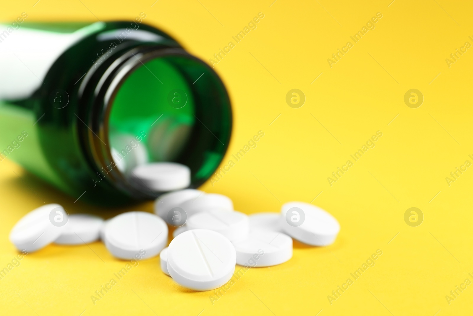 Photo of Medical bottle with antibiotic pills on yellow background, closeup. Space for text