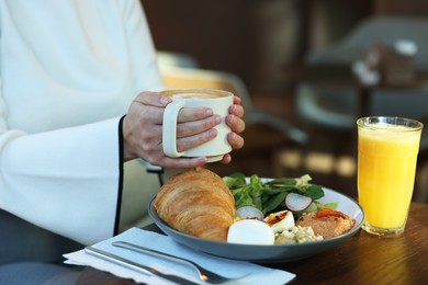 Photo of Woman having tasty breakfast in cafe, closeup