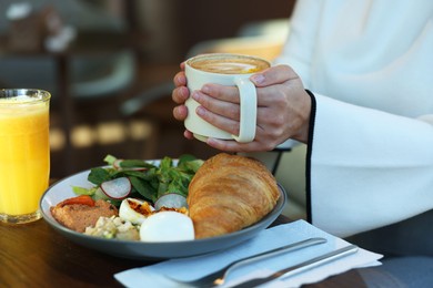 Photo of Woman having tasty breakfast in cafe, closeup