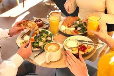 Photo of Women having tasty breakfast in cafe, closeup