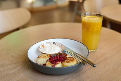 Photo of Delicious cottage cheese pancakes served on wooden table in cafe, closeup