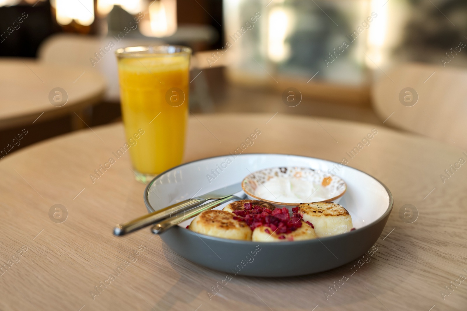 Photo of Delicious cottage cheese pancakes served on wooden table in cafe, closeup