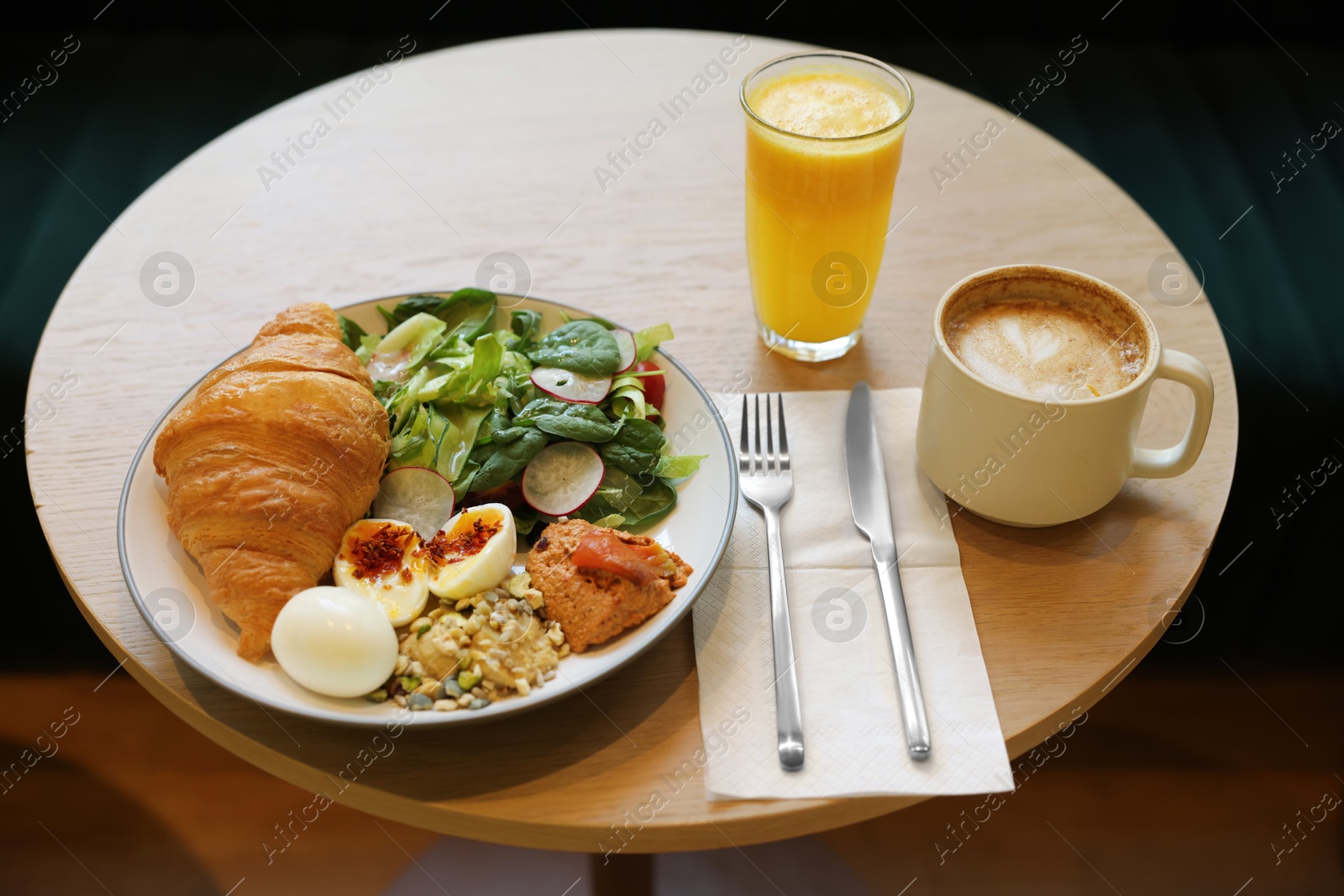 Photo of Tasty breakfast. Freshly baked croissant and salad served on wooden table in cafe