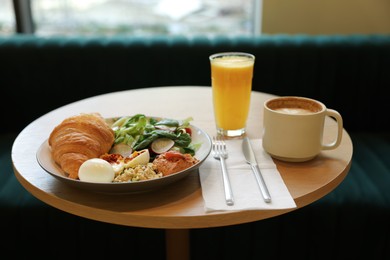 Photo of Tasty breakfast. Freshly baked croissant and salad served on wooden table in cafe