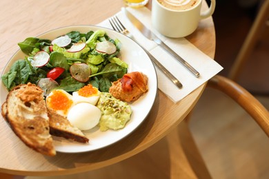 Photo of Tasty breakfast. Salad and eggs with red caviar served on wooden table in cafe, closeup