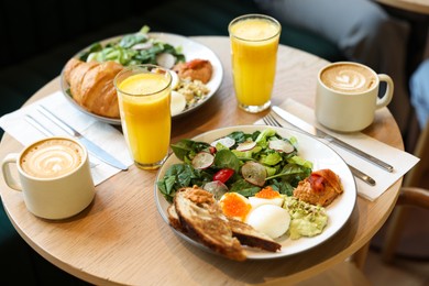 Photo of Tasty breakfast. Different meals and drinks served on wooden table in cafe, closeup