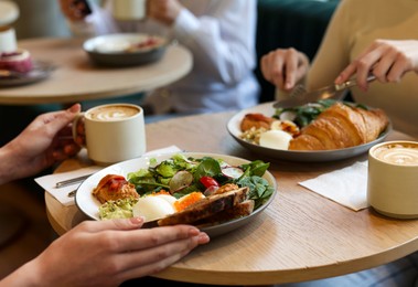 Photo of Women having tasty breakfast in cafe, closeup