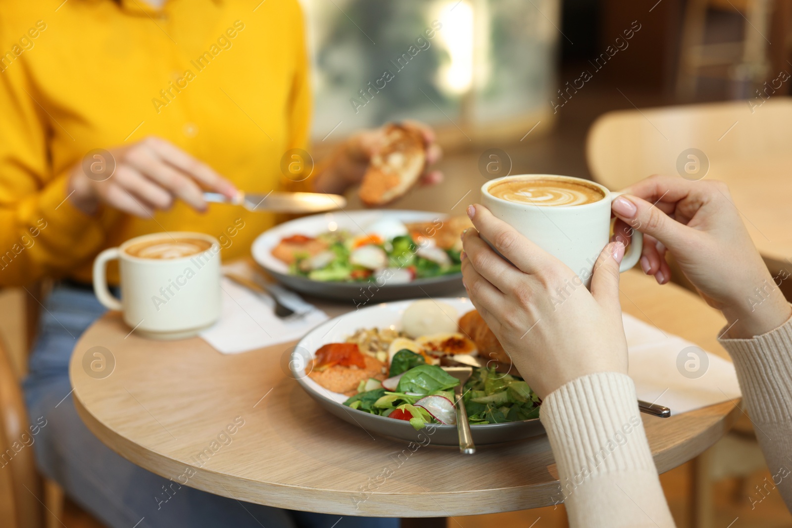 Photo of Women having tasty breakfast in cafe, closeup