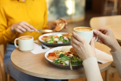 Photo of Women having tasty breakfast in cafe, closeup