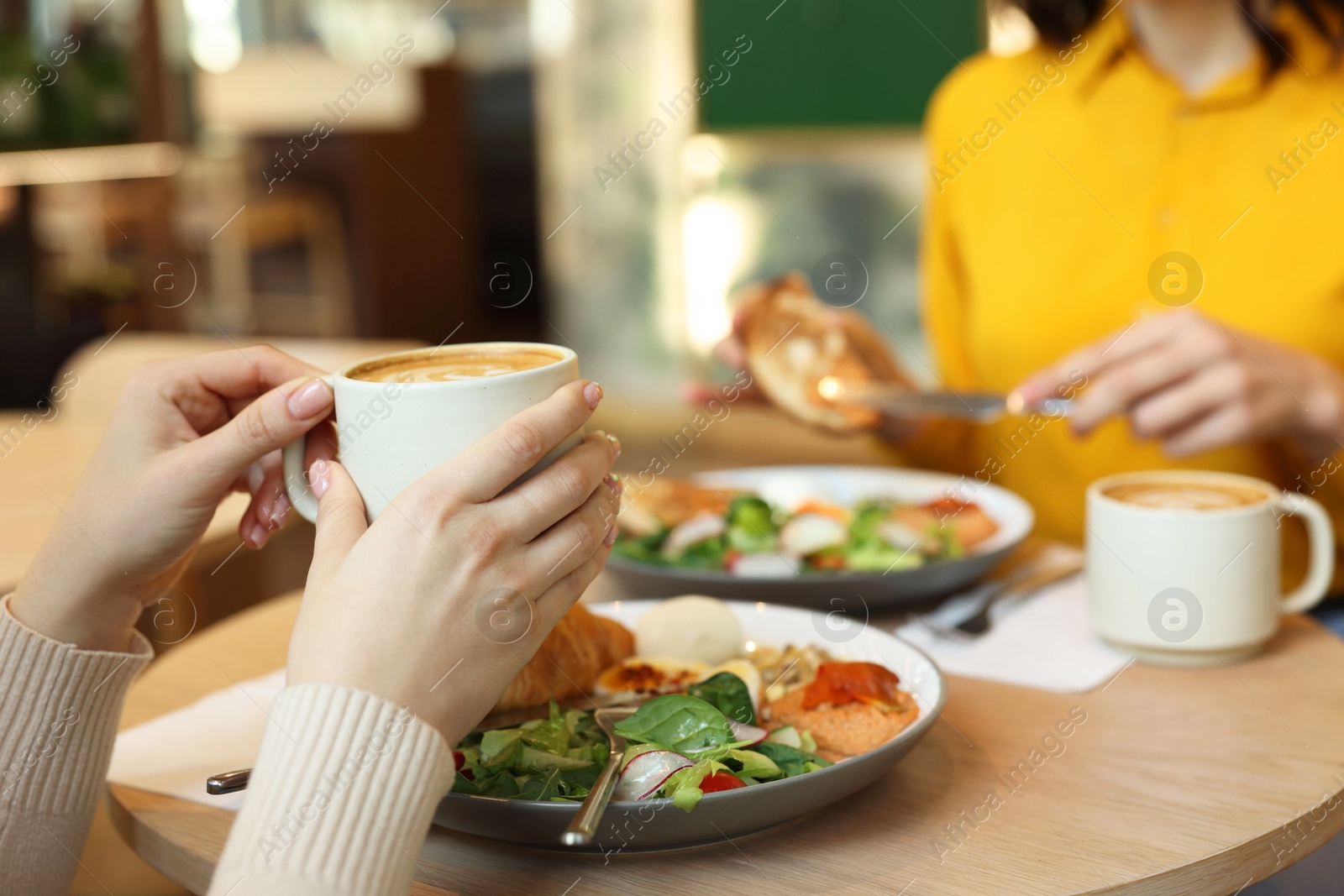 Photo of Women having tasty breakfast in cafe, closeup