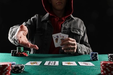 Photo of Man with cards and casino chips playing poker at gambling table, closeup