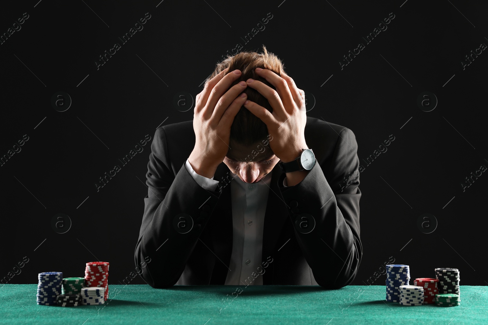 Photo of Sad young man with casino chips at gambling table. Poker concept