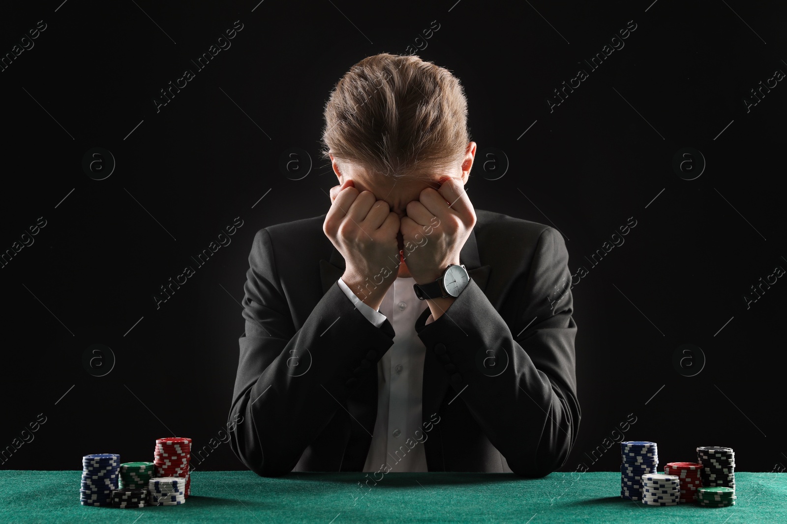 Photo of Sad young man with casino chips at gambling table. Poker concept