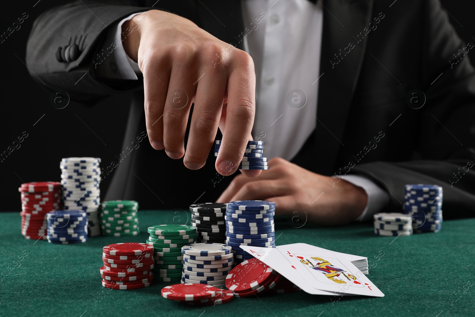 Photo of Man with cards and casino chips playing poker at gambling table, closeup