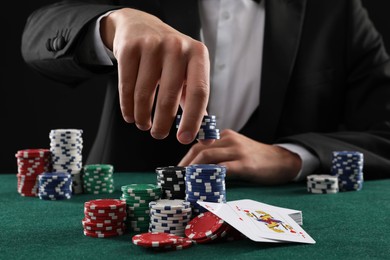 Photo of Man with cards and casino chips playing poker at gambling table, closeup