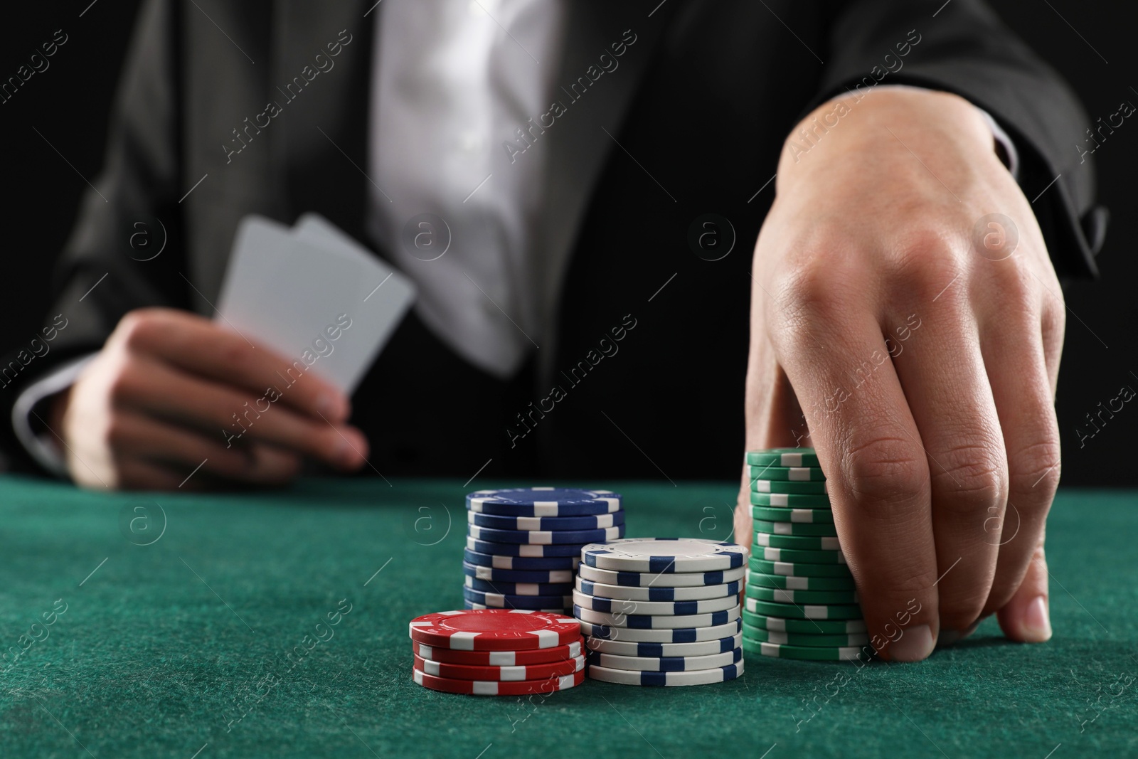 Photo of Man with cards and casino chips playing poker at gambling table, closeup