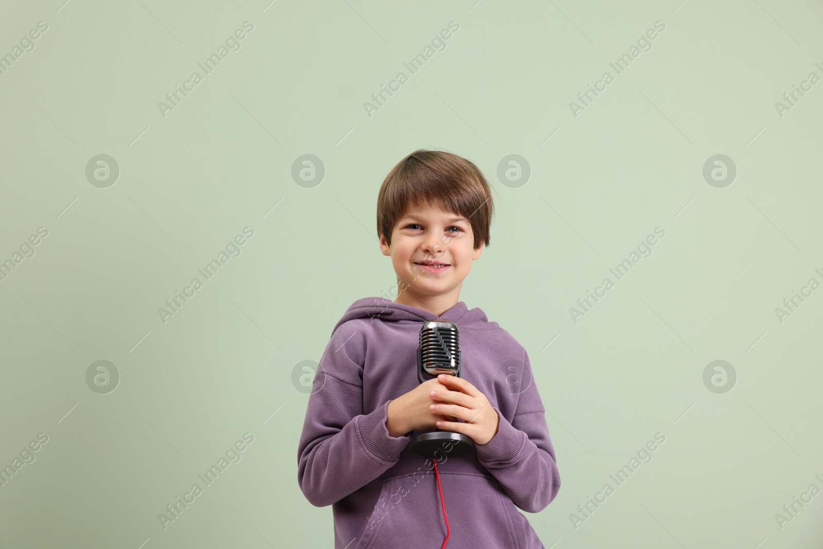 Photo of Smiling boy with microphone near green wall