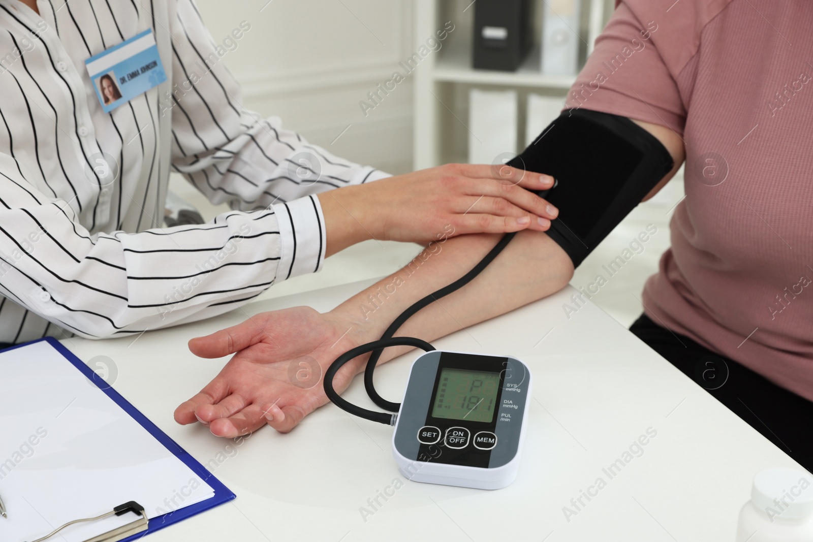 Photo of Nutritionist measuring overweight woman's blood pressure at desk in hospital, closeup