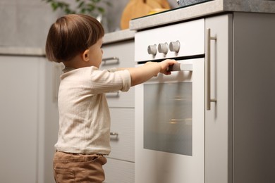 Little boy playing with oven in kitchen. Dangerous situation