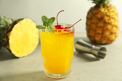 Photo of Tasty pineapple cocktail with mint and cherry in glass served on light table, closeup