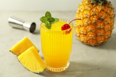 Photo of Tasty pineapple cocktail with mint and cherry in glass served on light table