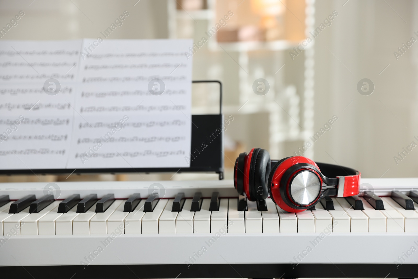 Photo of Synthesizer with music sheets and headphones indoors, closeup