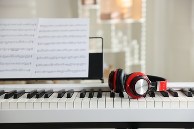 Photo of Synthesizer with music sheets and headphones indoors, closeup